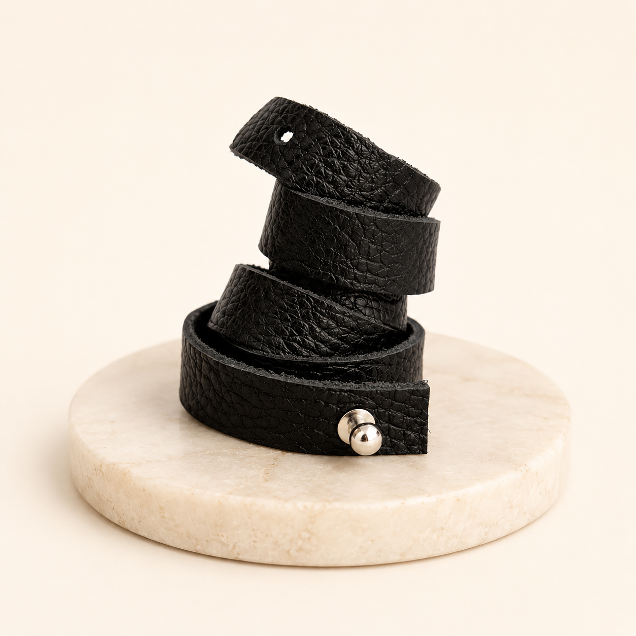 Black leather belt with silver buckle on a marble stand