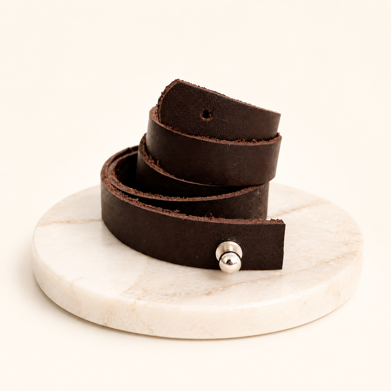 Brown leather belt with a silver buckle on a marble stand