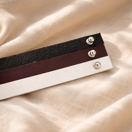 Leather hat bands with silver buttons on a beige fabric background