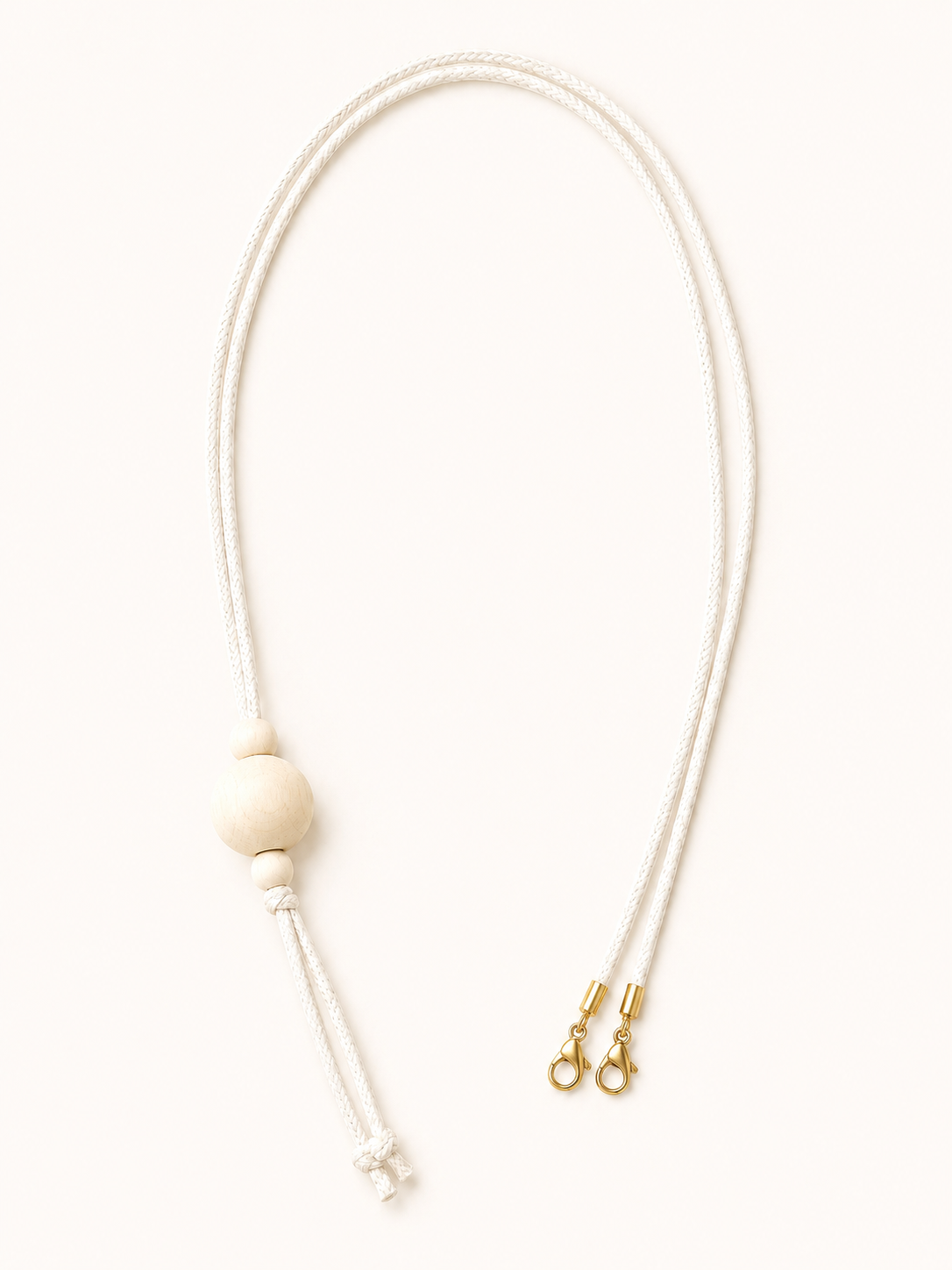  a beige pendant and with a white cord and a  gold clasp on a white background