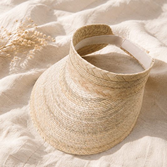 Beige straw visor on a textured beige surface